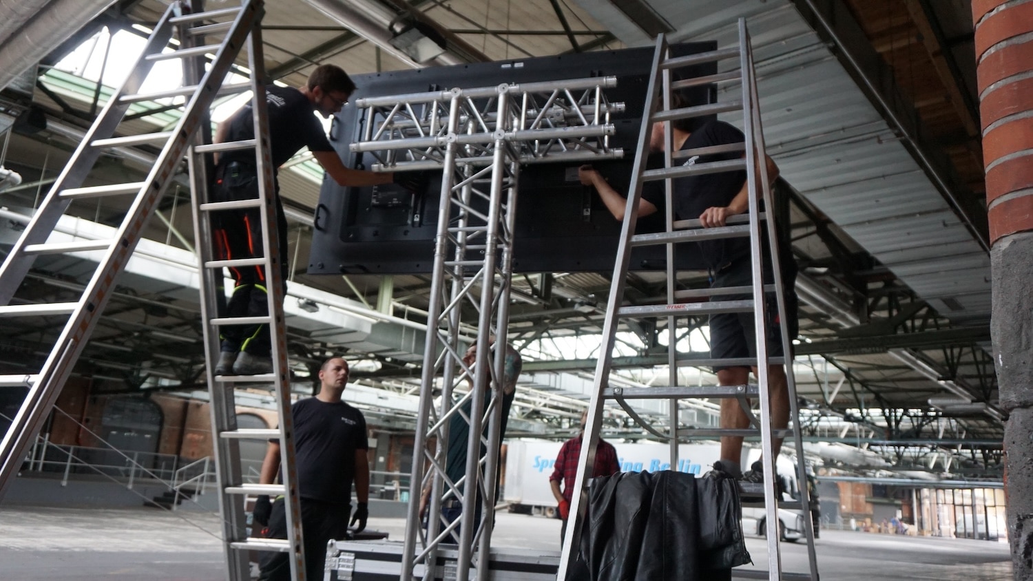 ein 95 Zoll Bildschirm wird vom Team der blue media an einem Traversen-Ständer montiert