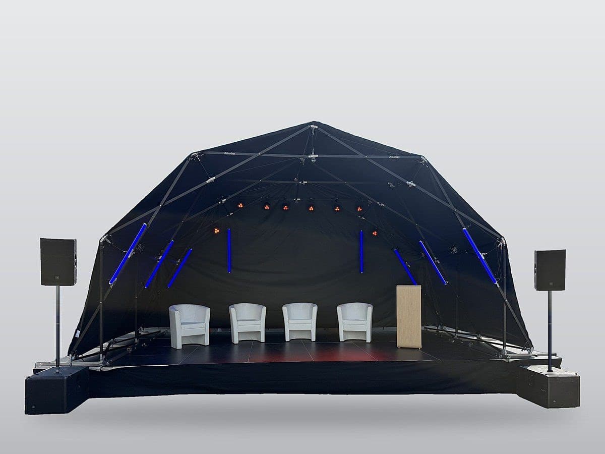 Bühne mit Rundbogendach mieten Berlin: 8 m breite Open-Air-Bühne mit schwarzem Bogendach, eingerichtet für eine Podiumsdiskussion mit vier Sesseln, Rednerpult und PA
