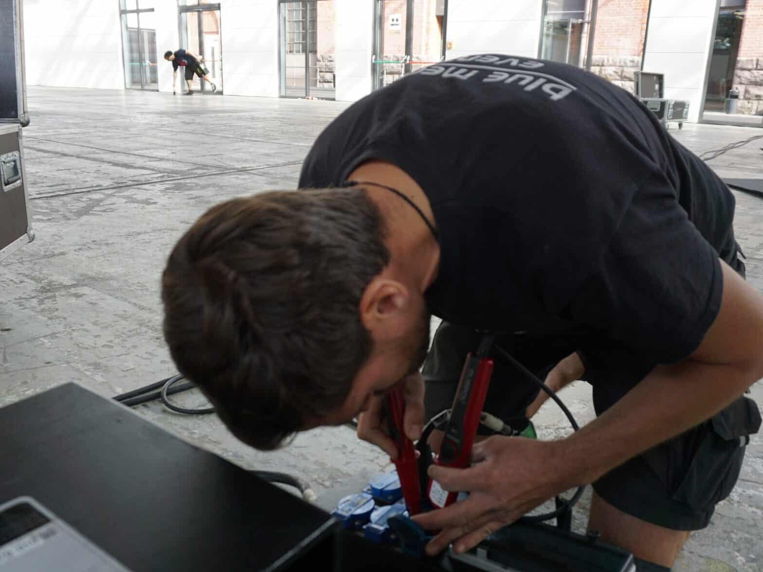 Praktikum Veranstaltungstechnik Berlin: Junger Techniker konfektioniert Kabel beim Aufbau einer Veranstaltung