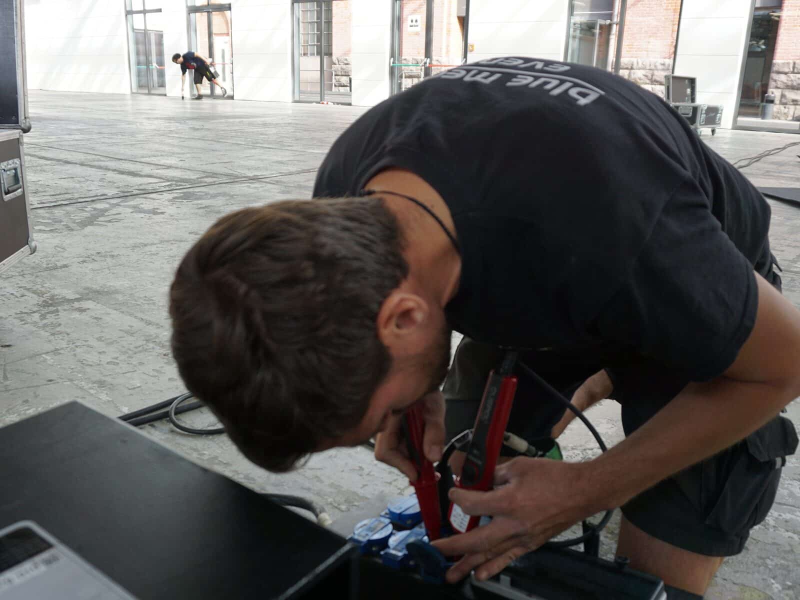 Praktikum Veranstaltungstechnik Berlin: Junger Techniker konfektioniert Kabel beim Aufbau einer Veranstaltung